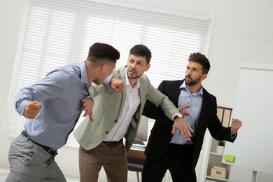 Man interrupting colleagues fight at work in office
