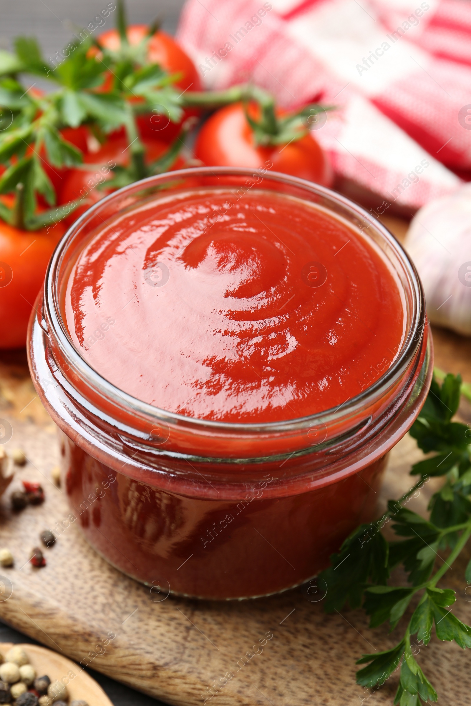 Photo of Tasty ketchup, fresh tomatoes, parsley and spices on grey wooden table