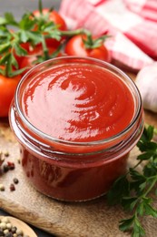 Photo of Tasty ketchup, fresh tomatoes, parsley and spices on grey wooden table