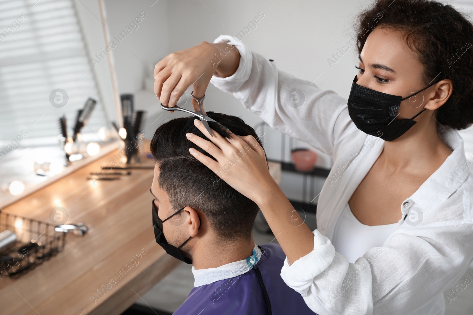 Photo of Professional stylist working with client in salon. Hairdressing services during Coronavirus quarantine