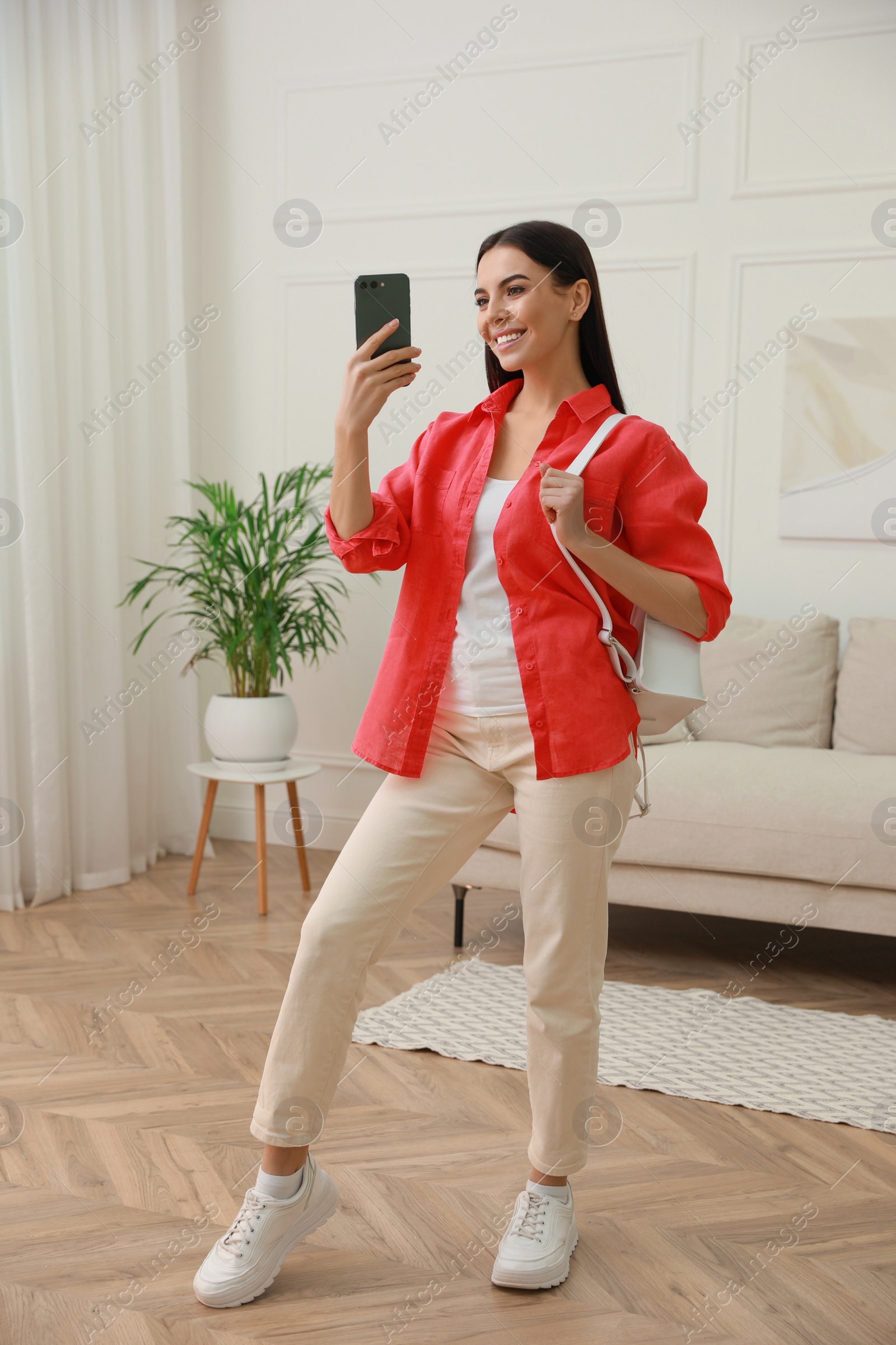 Photo of Young woman taking mirror selfie in stylish outfit at home. Morning routine