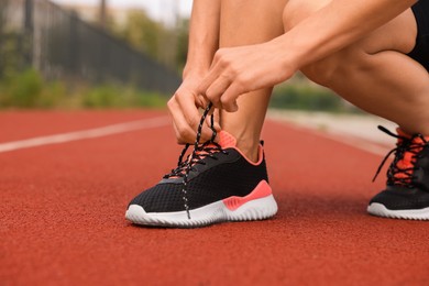 Woman tying shoelaces before training outdoors. closeup. Space for text