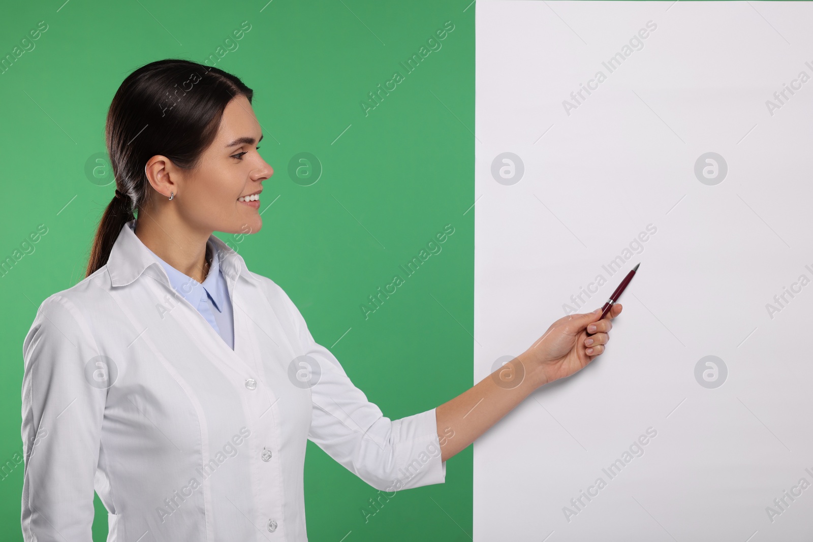 Photo of Ophthalmologist pointing at blank banner on green background, space for text