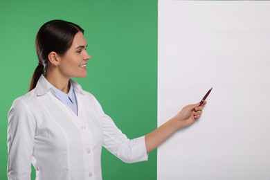 Ophthalmologist pointing at blank banner on green background, space for text