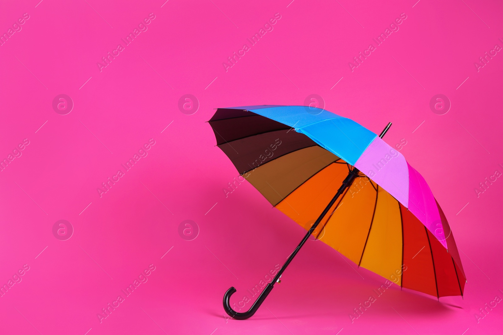Photo of Colorful umbrella on pink background. Space for text