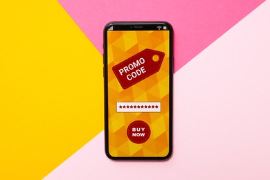 Photo of Smartphone with activated promo code on colorful background, top view