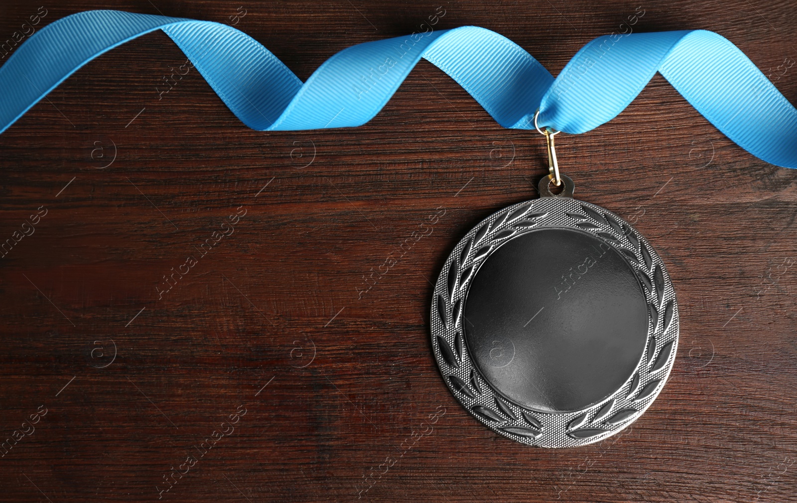 Photo of Silver medal on wooden background, top view. Space for design