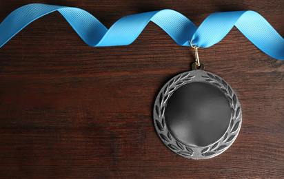 Silver medal on wooden background, top view. Space for design