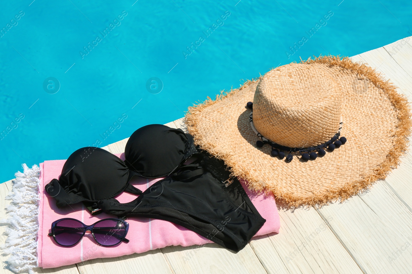 Photo of Beach accessories on wooden deck near swimming pool. Space for text