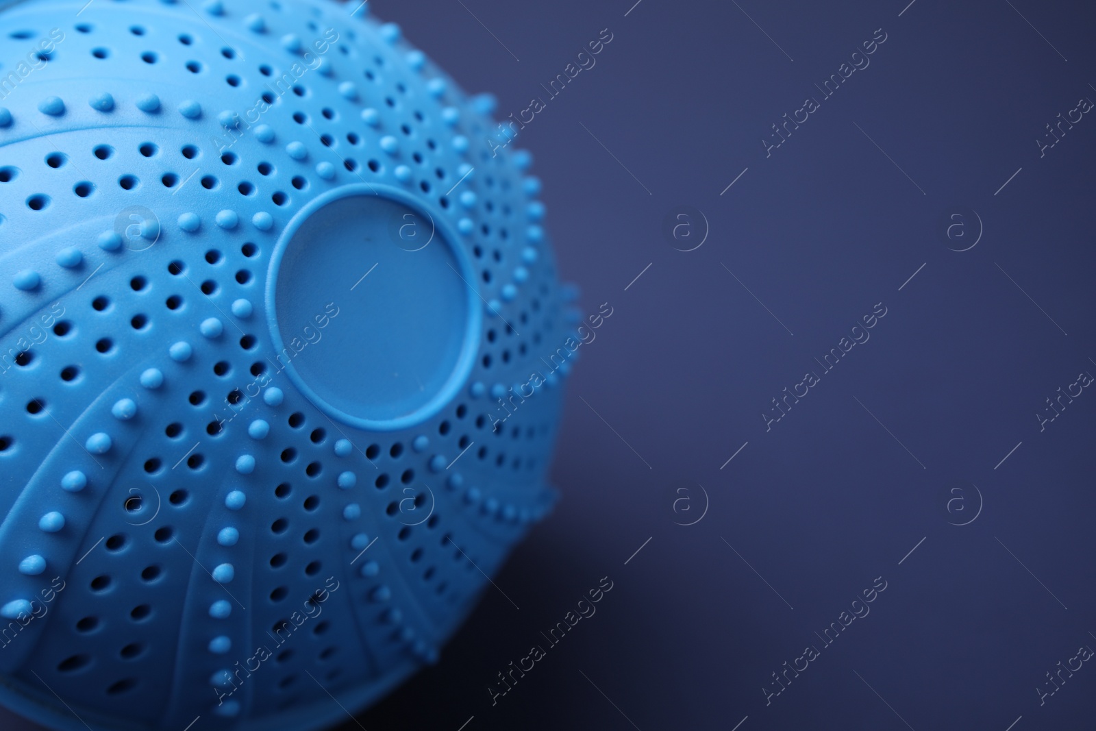 Photo of Laundry dryer ball on dark blue background, closeup. Space for text