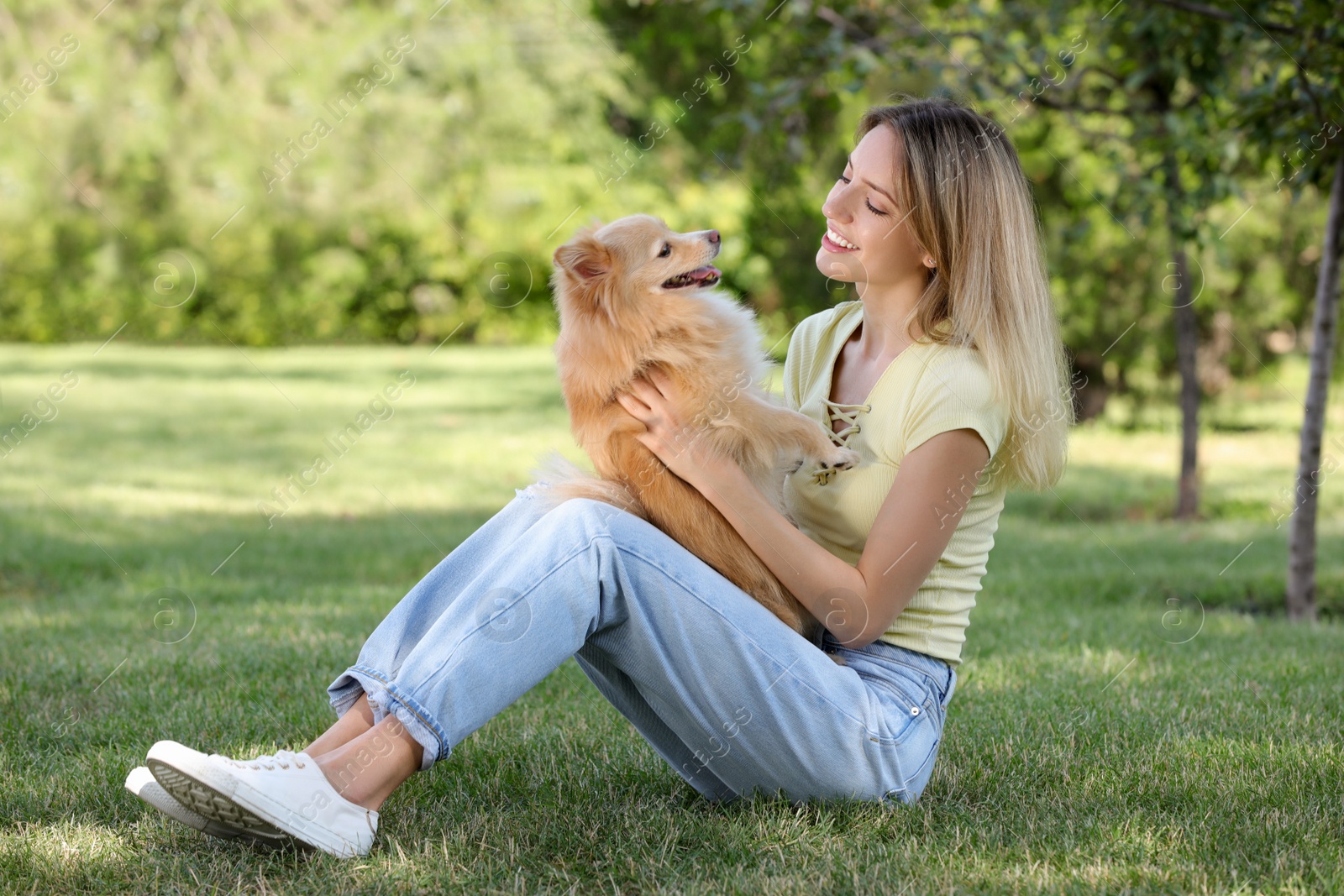 Photo of Young woman with her cute dog on green grass in park