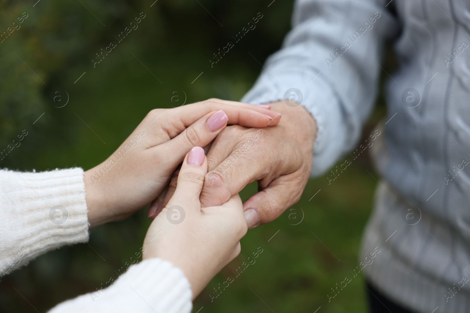 Photo of Trust and support. Woman with man joining hands outdoors, closeup