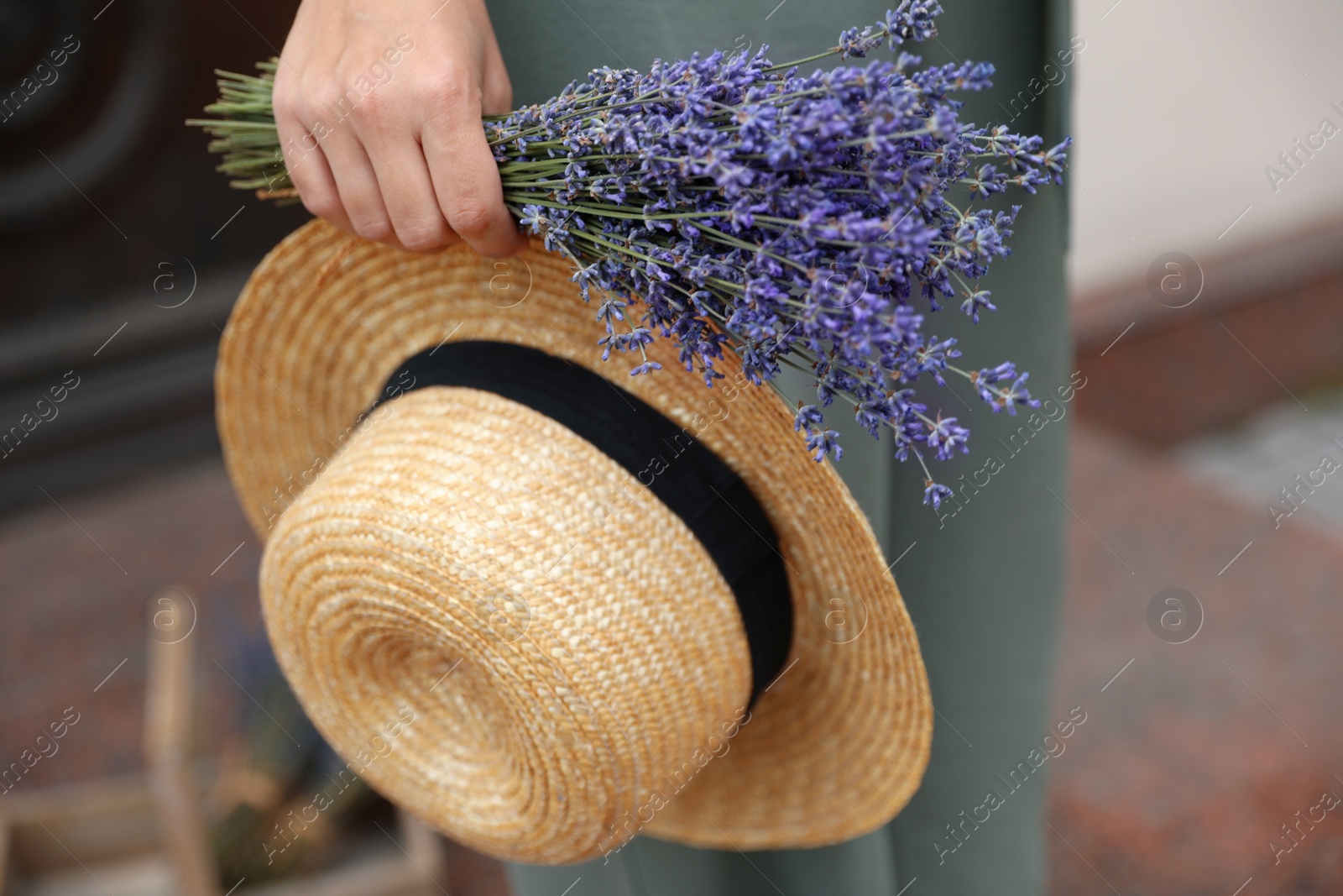 Photo of Young woman with lavender flowers and straw hat outdoors, closeup