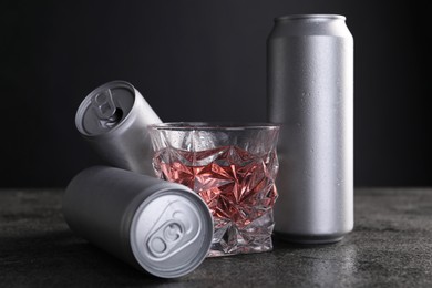 Energy drink in glass and aluminium cans on grey table, closeup