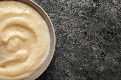 Photo of Bowl with delicious semolina pudding on grey table, top view. Space for text