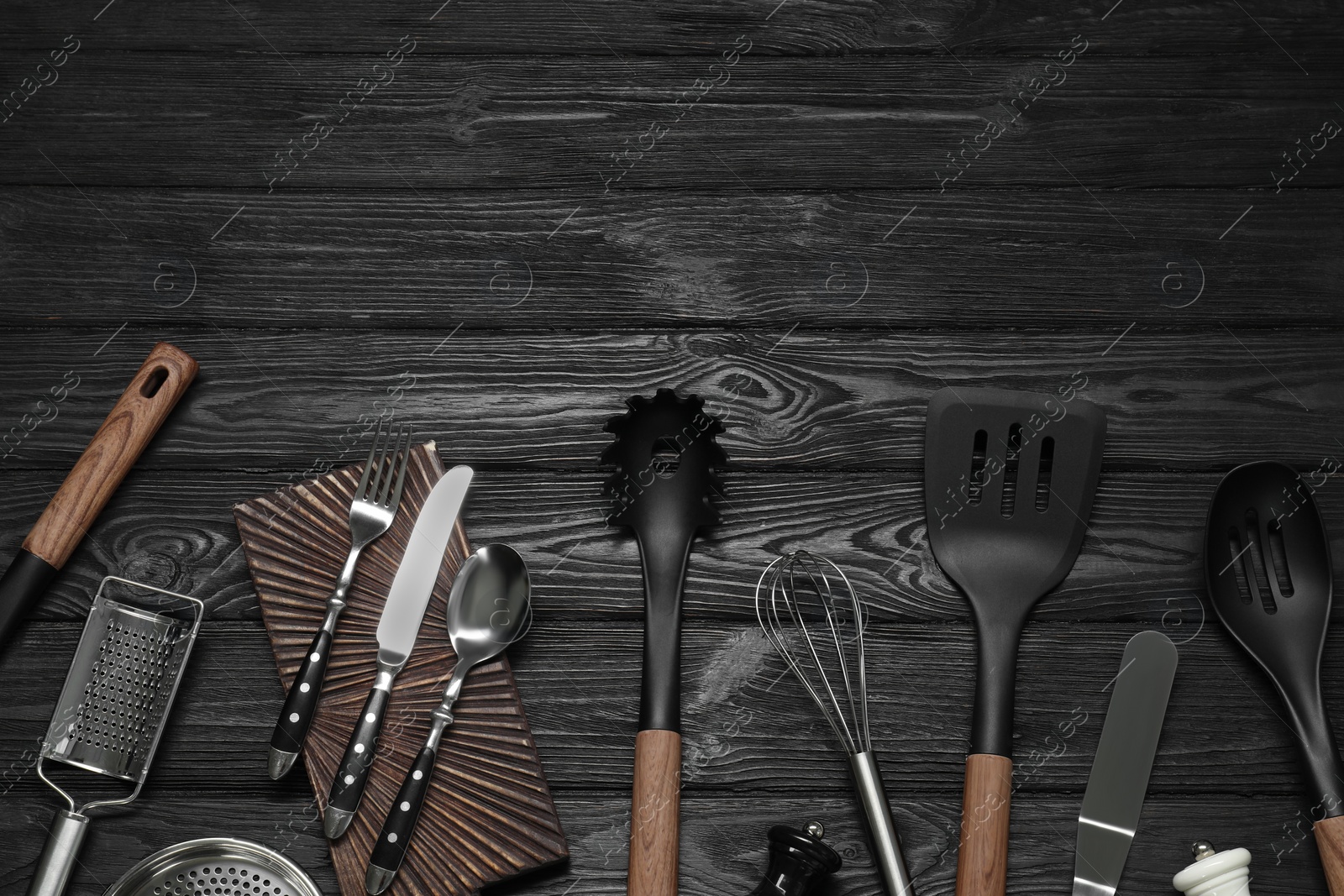 Photo of Set of different kitchen utensils on black wooden table, flat lay with space for text