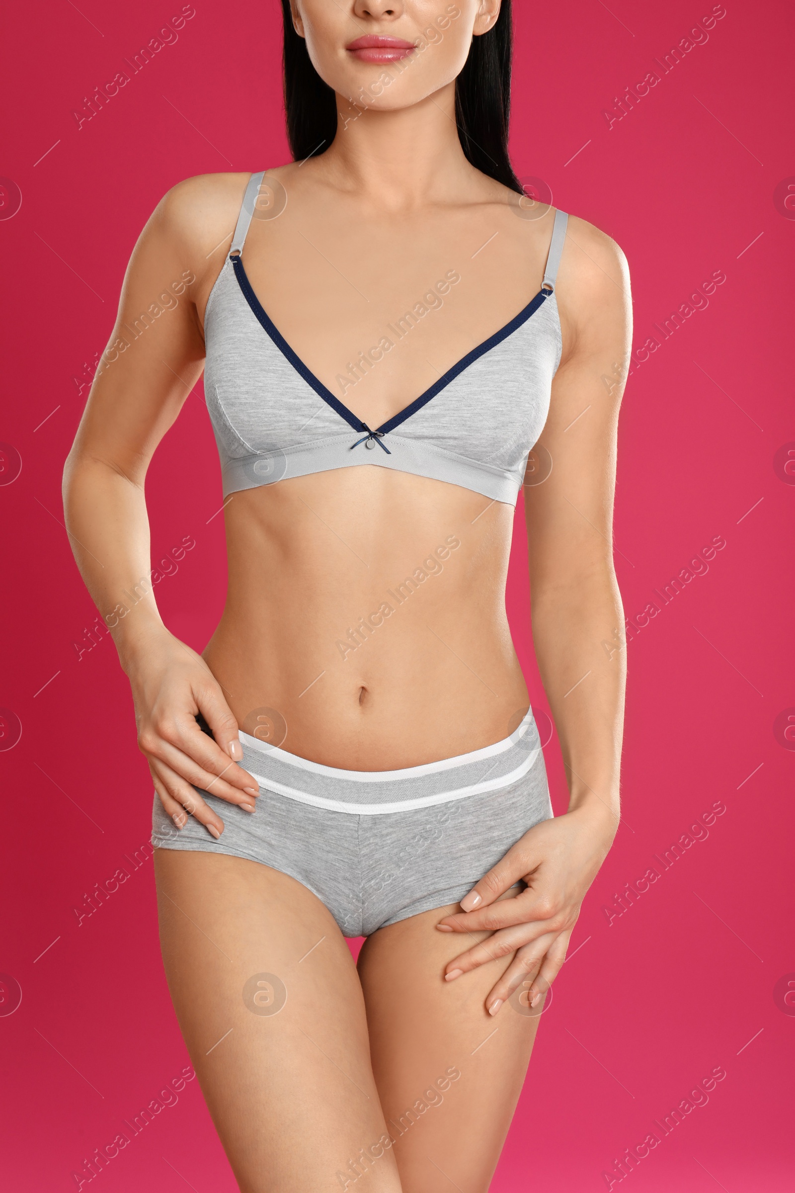 Photo of Young woman in grey sportive underwear on pink background, closeup