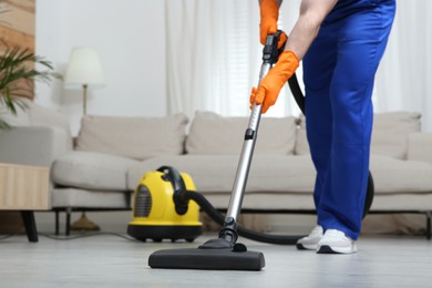 Photo of Janitor in uniform vacuuming floor indoors, closeup