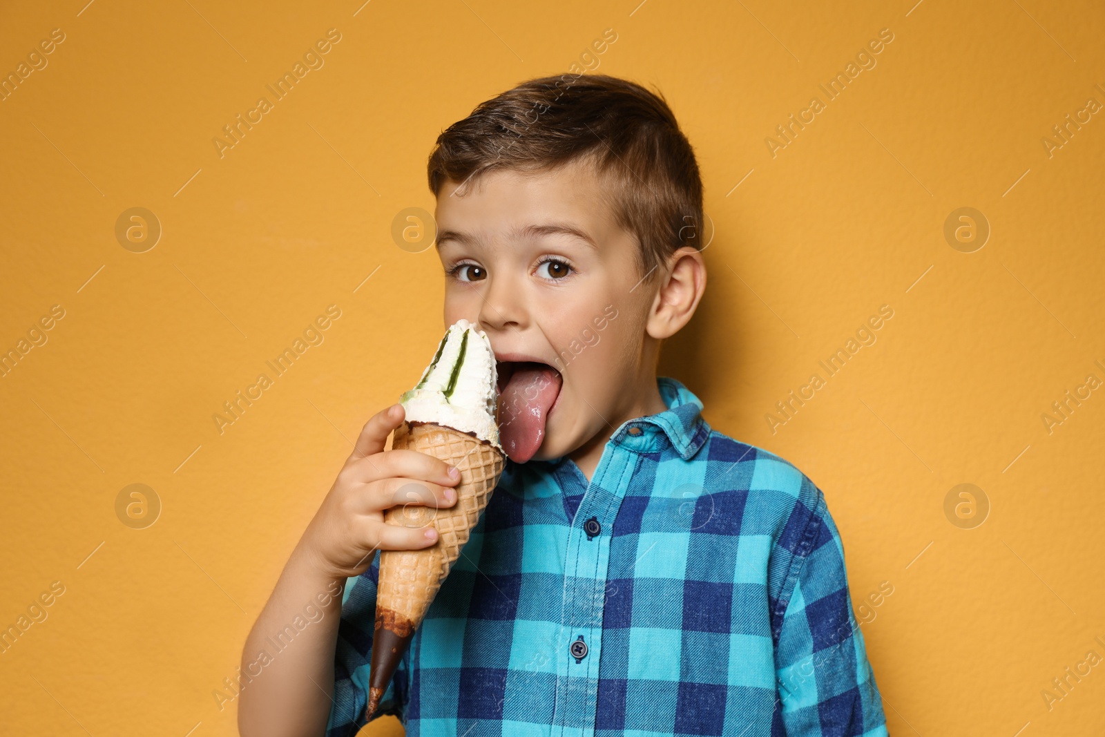 Photo of Adorable little boy with delicious ice cream against color background