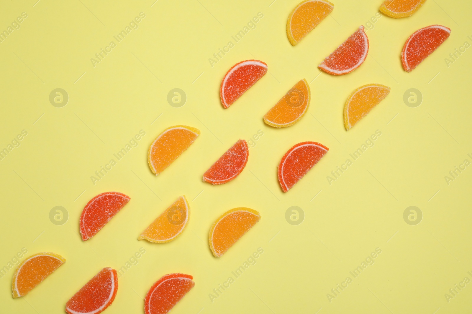 Photo of Many sweet jelly candies on pale yellow background, flat lay