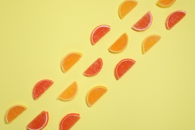 Many sweet jelly candies on pale yellow background, flat lay