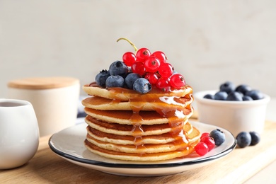 Delicious pancakes with fresh berries and syrup on table