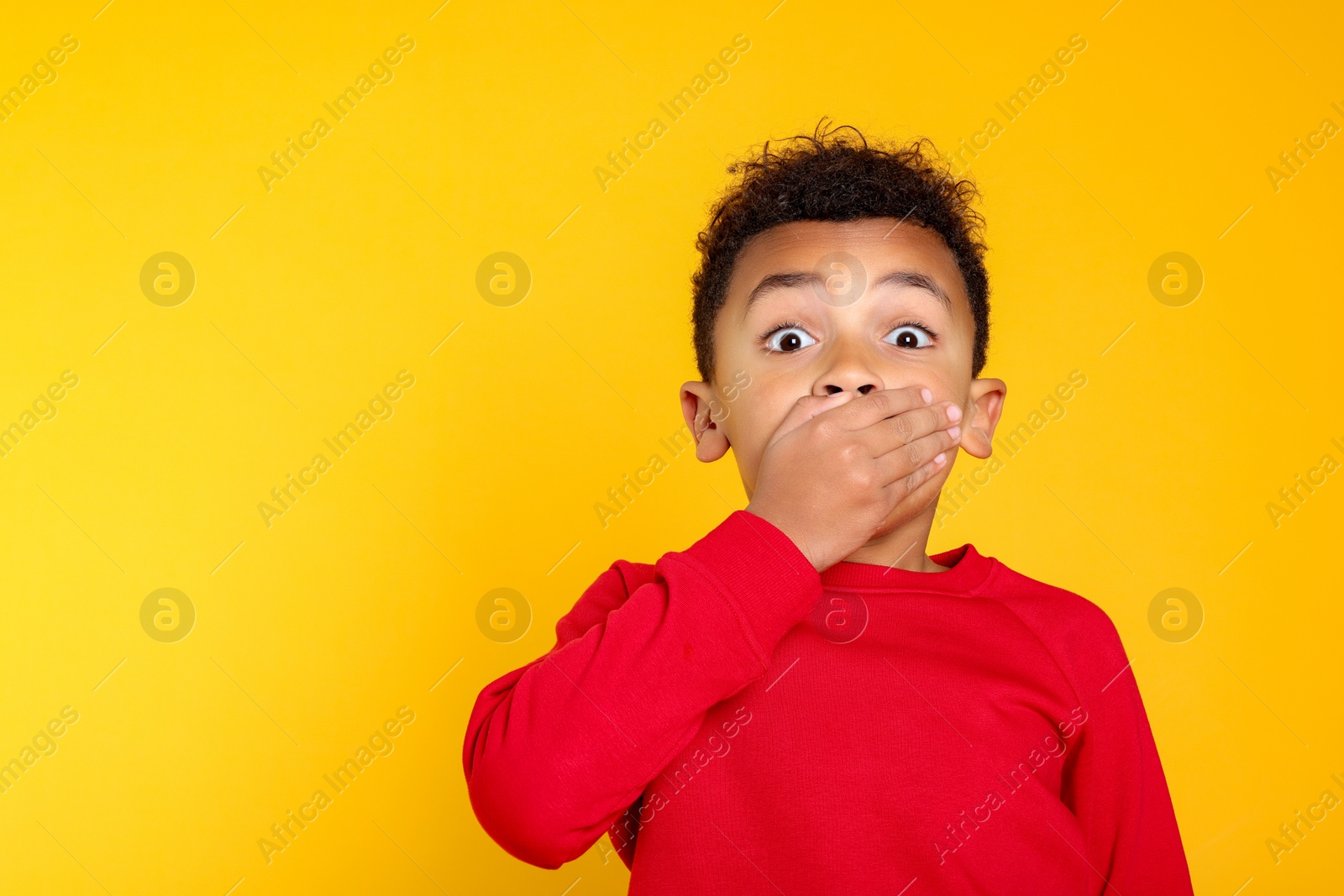 Photo of Emotional African-American boy on yellow background. Space for text