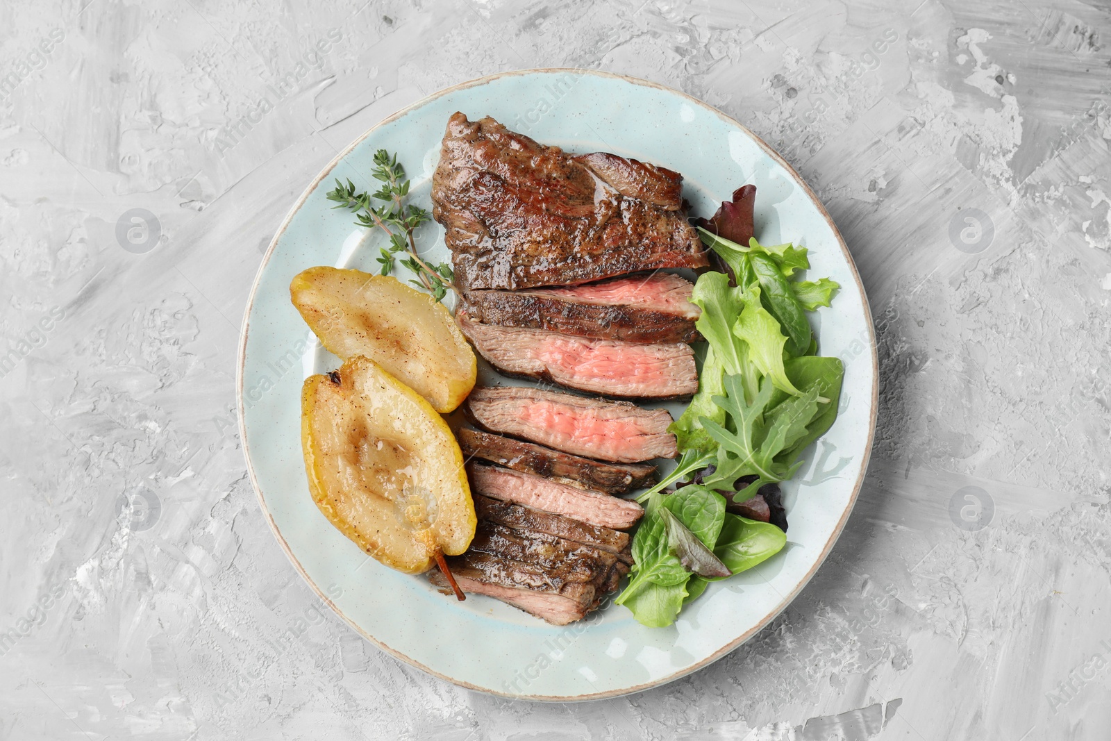 Photo of Pieces of delicious roasted beef meat, caramelized pear and greens on light textured table, top view