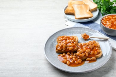 Toasts with delicious canned beans on white wooden table, space for text