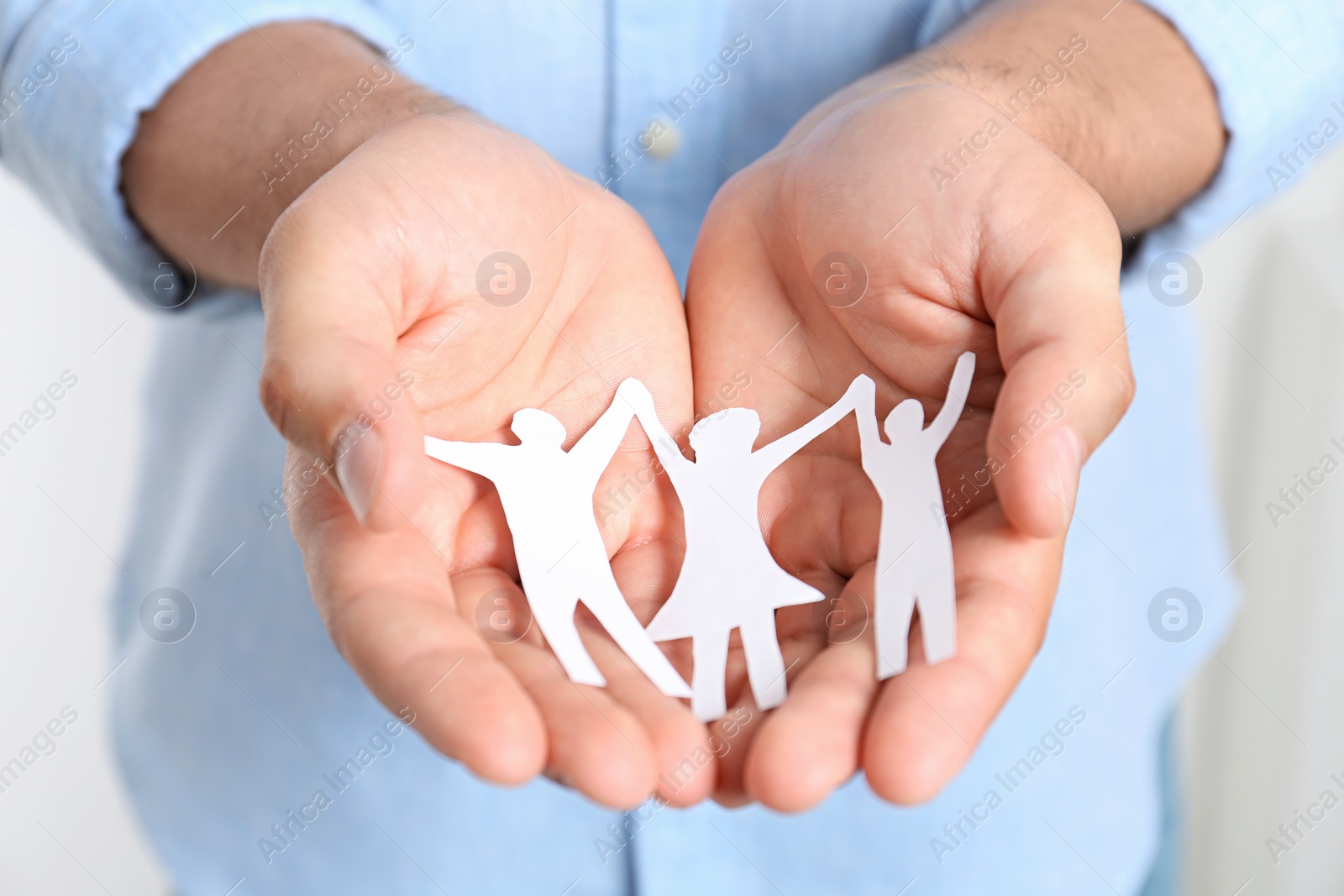 Photo of Young man holding paper family figure, closeup of hands