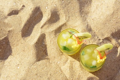 Photo of Glasses of refreshing drink with kiwi and mint on sand, top view. Space for text