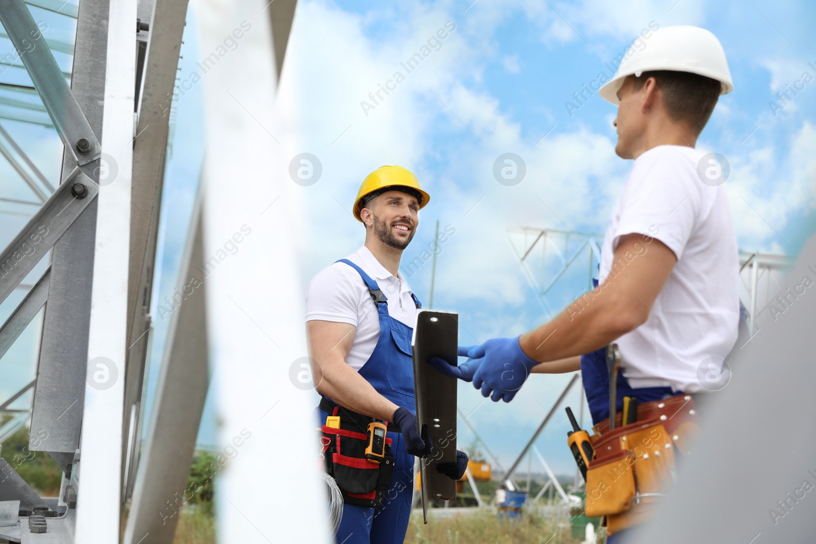 Photo of Workers building high voltage tower construction outdoors. Installation of electrical substation