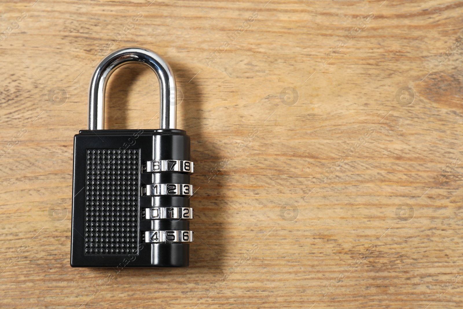 Photo of One steel combination padlock on wooden table, top view. Space for text