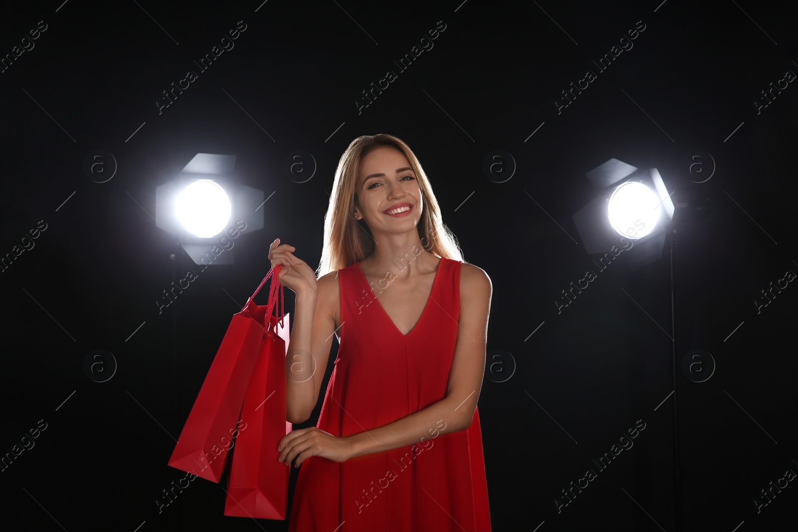 Photo of Happy young woman with shopping bags on dark background. Black Friday Sale