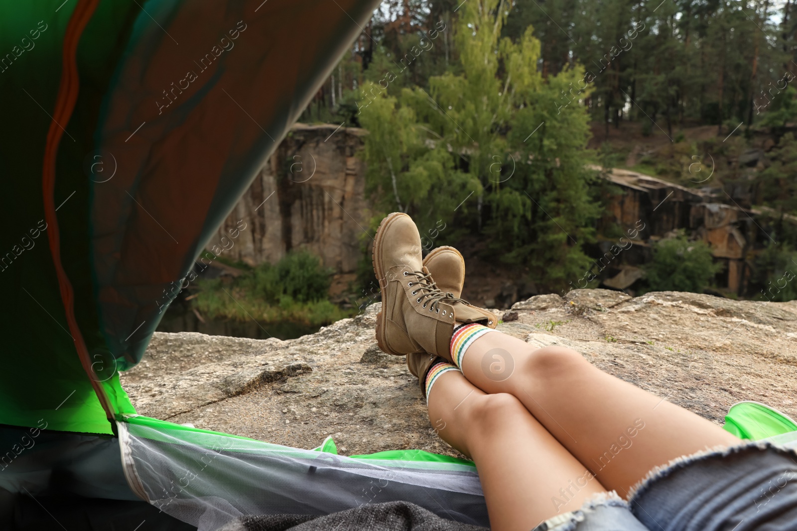 Photo of Young woman resting in camping tent, view from inside