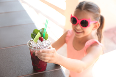 Photo of Girl with delicious refreshing drink outdoors, focus on plastic cup