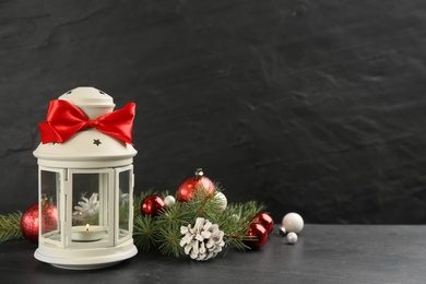 Photo of Christmas lantern with burning candle and festive decor on black background. Space for text