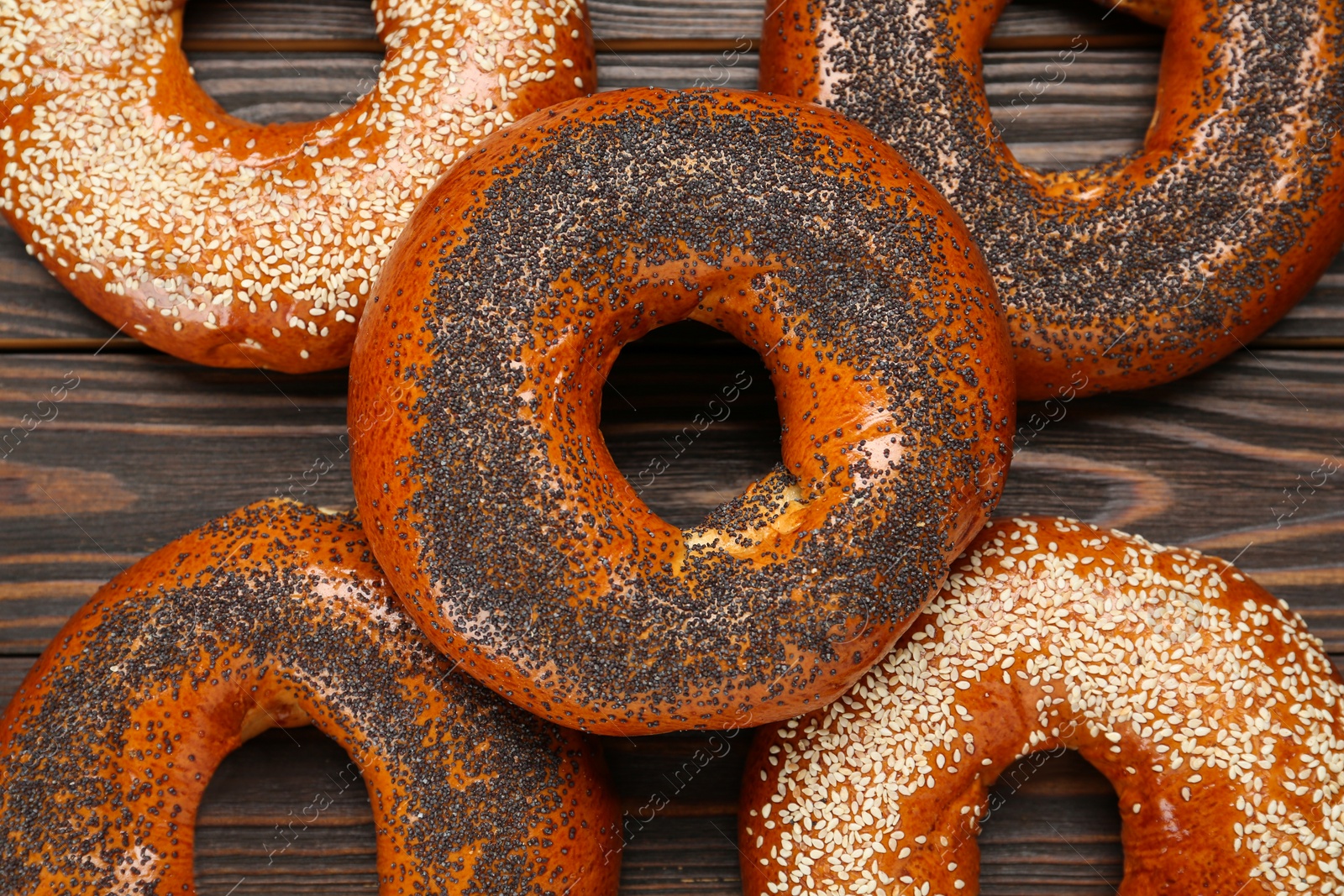 Photo of Many delicious fresh bagels on wooden table, flat lay