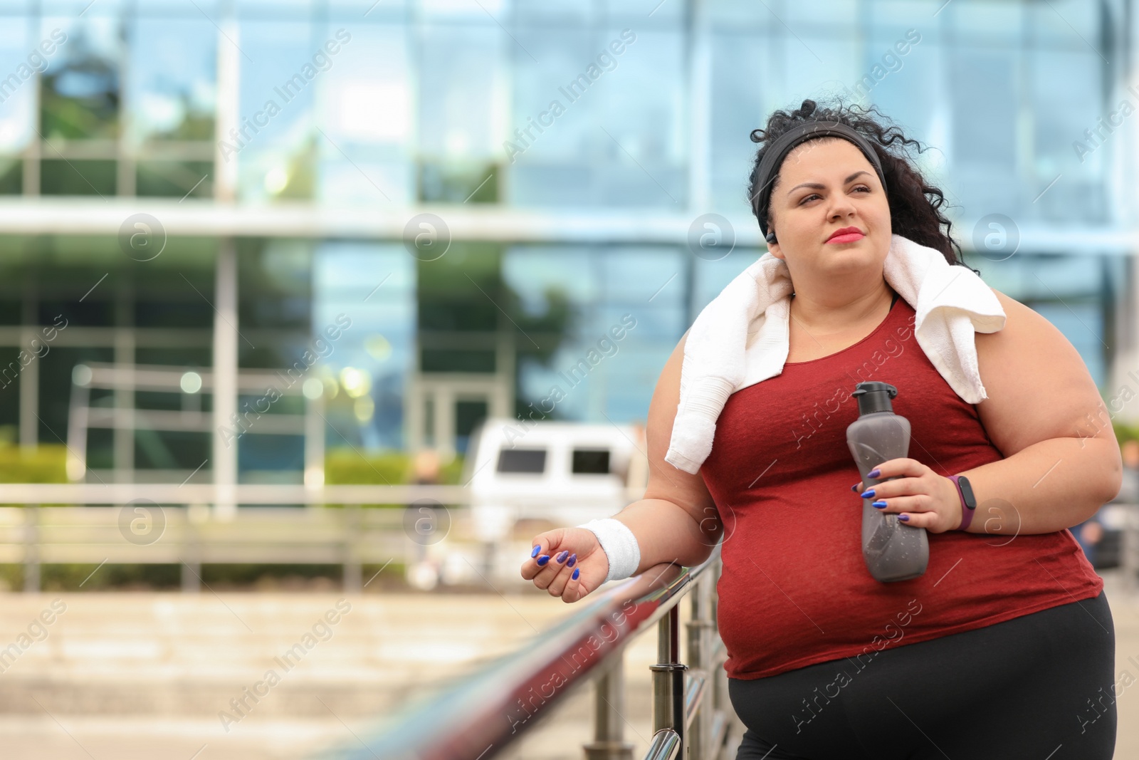 Photo of Beautiful overweight woman in sportswear with bottle and towel outdoors