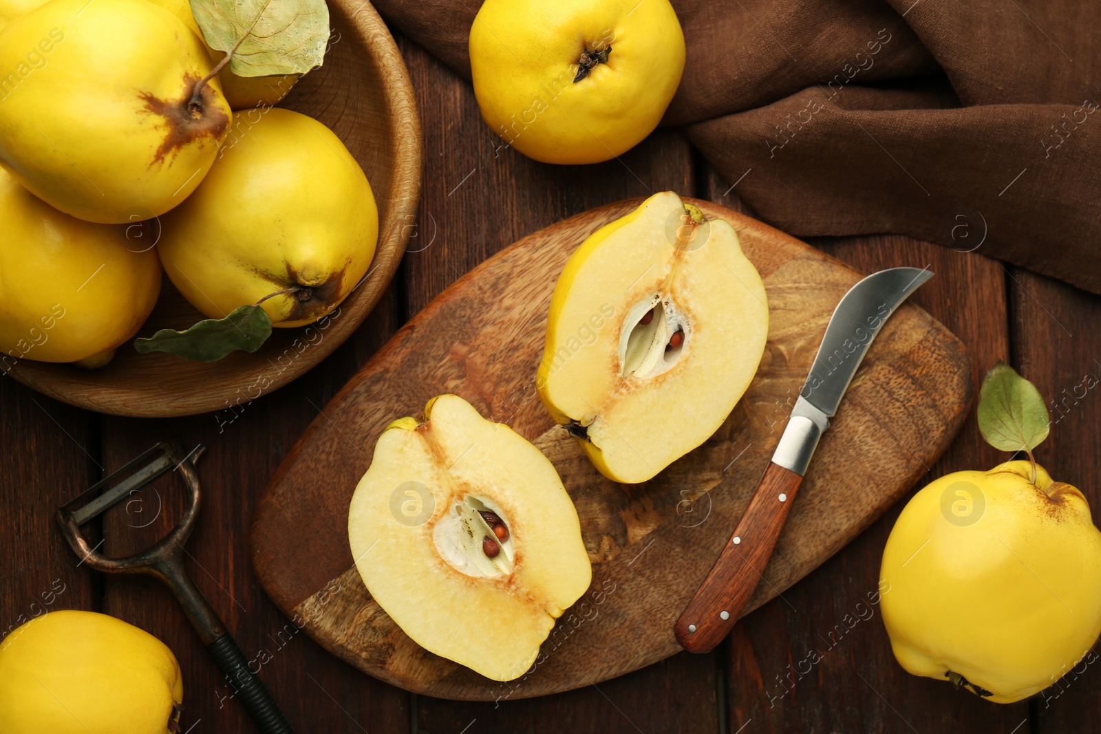 Photo of Tasty ripe quince fruits, peeler and knife on wooden table, flat lay