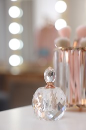 Photo of Bottle of perfume on white table in makeup room