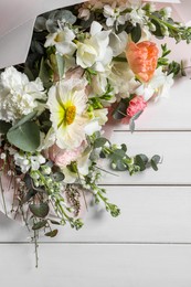 Bouquet of beautiful flowers on white wooden table, top view