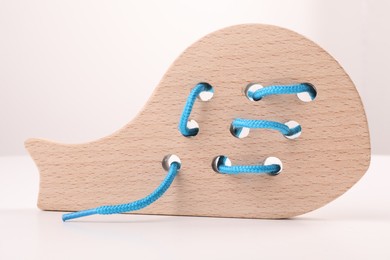 Photo of Motor skills development. Wooden lacing toy on white table, closeup