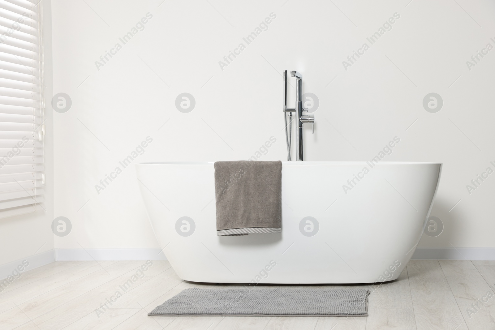 Photo of Stylish bathroom interior with ceramic tub and terry towel