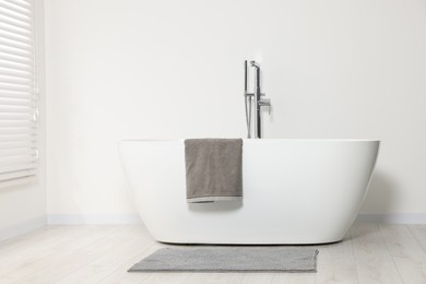 Stylish bathroom interior with ceramic tub and terry towel