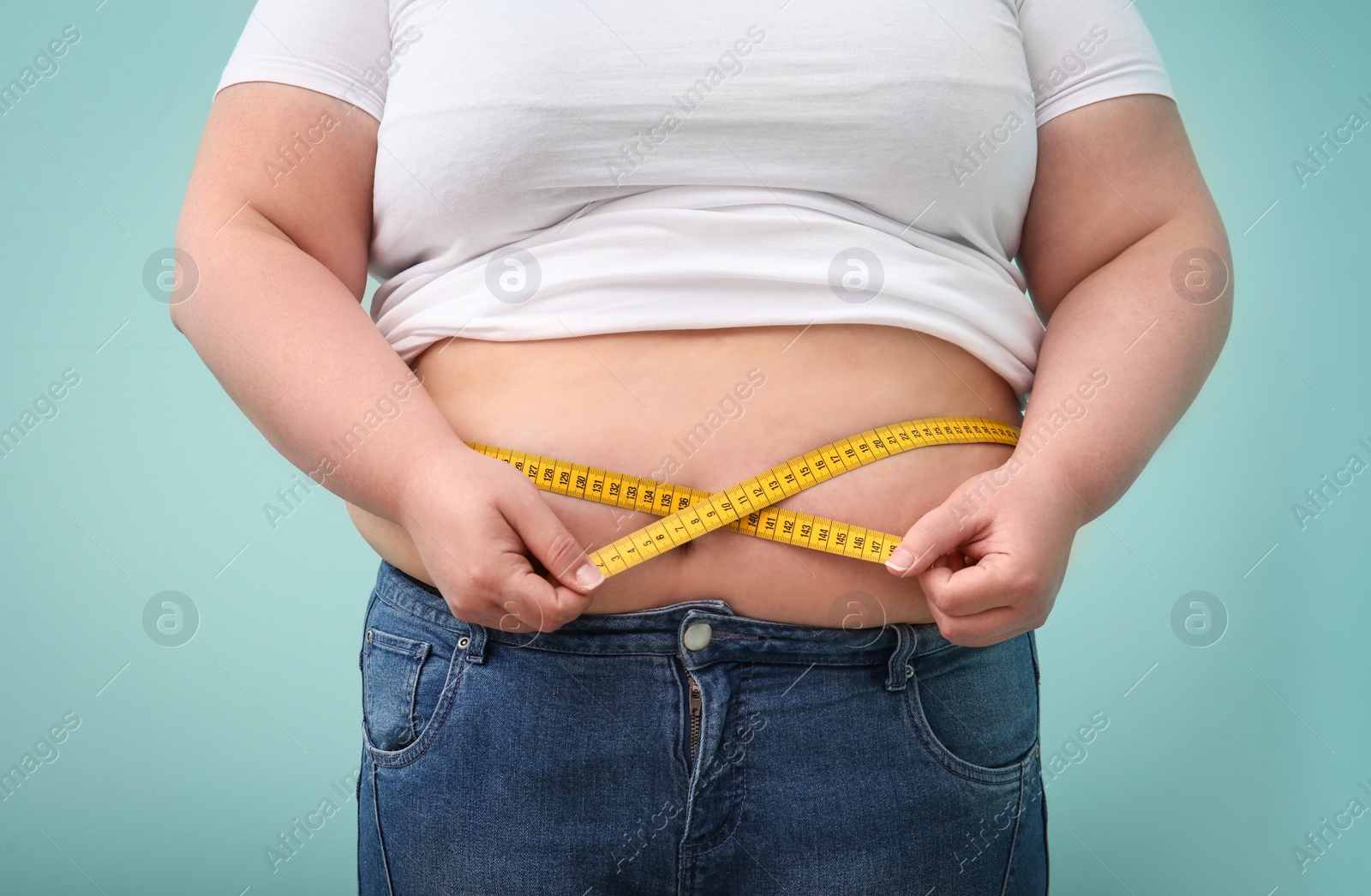 Photo of Overweight woman with measuring tape on color background