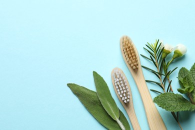 Photo of Bamboo toothbrushes, beautiful flowers and herbs on turquoise background, flat lay. Space for text