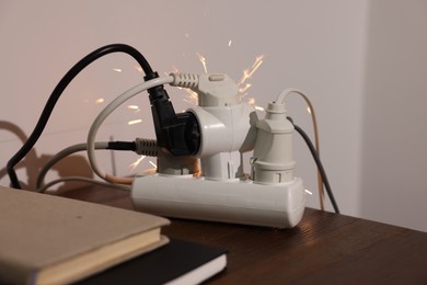 Inflamed plug in power strip indoors on wooden table. Electrical short circuit
