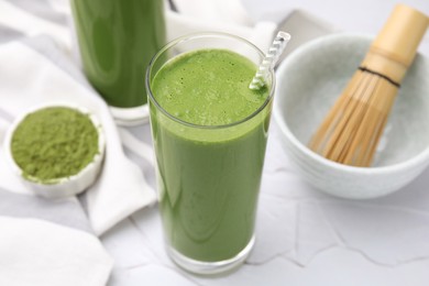 Photo of Glass of tasty matcha smoothie on white textured table, closeup