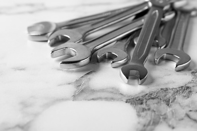 Photo of New wrenches on marble background, closeup with space for text. Plumber tools